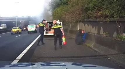 Mother hugs toddler next to the A20 in Spijkenisse after bystander Vincent Bakker rescued him and baby sibling from a burning car, 20 Oct 2016 (Photo: Screenshot/YouTube)