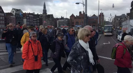 Three groups of tourists on walking tours try to cross the Damrak in Amsterdam Centrum, 13 Apr 2017