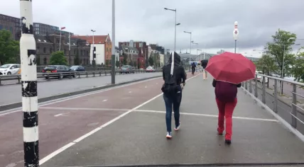 Tourists walk through light morning rain on their way to Amsterdam Centraal, 6 Jun 2017