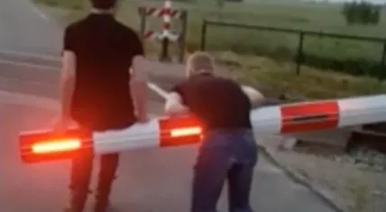 Teens hanging off a boom at a rail crossing in Friesland