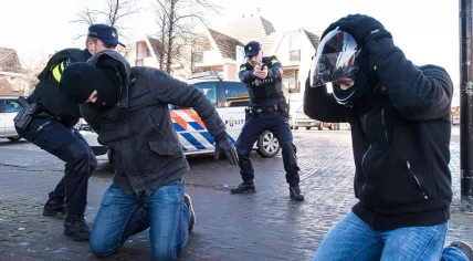 Police officer points his firearm at a suspect during an arrest