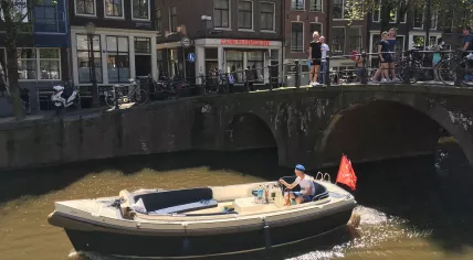 A boat cruising down Oudezijds Voorburgwal in Amsterdam Centrum, 8 May 2018