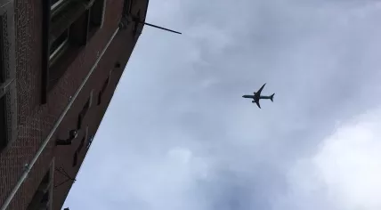 A KLM-branded Boeing 787-9 Dreamliner flying over Amsterdam Centrum on approach to Schiphol Airport during a windy morning. The flight from Bogotá and Cartagena, Colombia was one of several passenger aircraft to arrive late, 4 March 2019