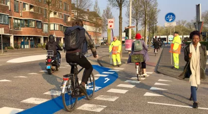 A scooter rider and several bicyclists approach a snorfiets checkpoint in Amsterdam Centrum, 8 April 2019