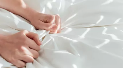 Hands clutching bed linen 