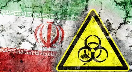 Cracked wall with the Iranian flag and a bio-hazard sign painted on it 