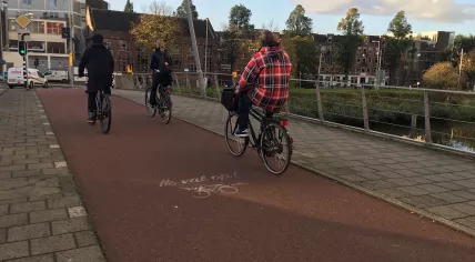 Cyclists in Amsterdam Oost riding past the "ik val op!" road marker, 28 Oct 2019