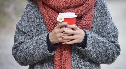 A woman bundled up with a warm drink