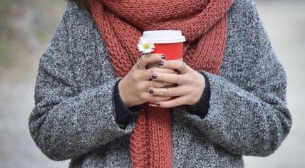 A woman bundled up with a warm drink