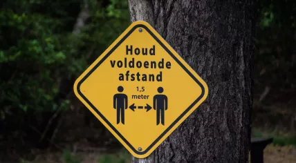 A concept sign to promote social distancing on a nature trail. May 2020