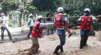 Red Cross rescue workers helping a child after hurricane Eta in Central America