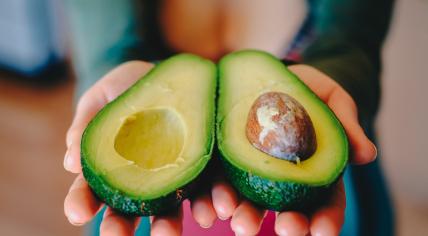 A halved avocado held in two hands