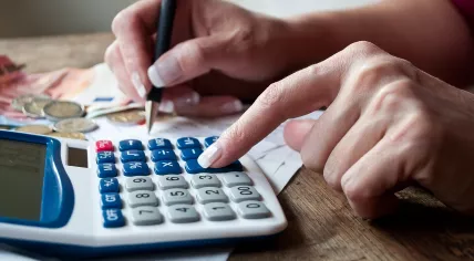 Closeup of woman with calculator and money on desk