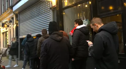 People standing in line outside a coffeeshop set to close for coronavirus regulations