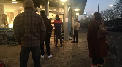 People lined up outside an Amsterdam Oost Albert Heijn location, that made people wait outside at a distance until other customers left the store, 25 March 2020