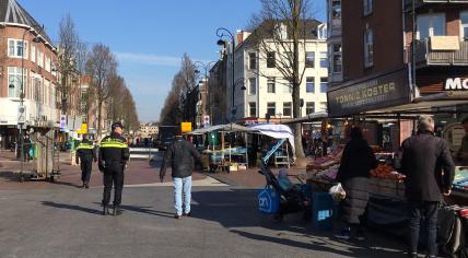 Covid-19: Police patrol the Dappermarkt in Amsterdam to make sure shoppers keep 1.5 meters apart, 26 March 2020