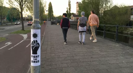 Covid-19: Three young men walk past a 'Fight the Virus' sign on Panamalaan in Amsterdam, 22 April 2020