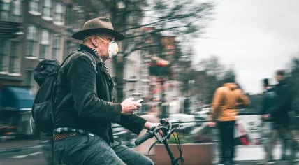 A man cycling through Amsterdam wearing a respirator-style medical mask