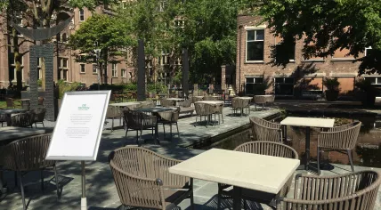 Cafe de Tropen in Amsterdam expanding its terrace into the courtyard of the Tropenmuseum in preparation for terraces reopening on 1 June 2020. Sign asks visitors to not move the tables which were organized with social distancing in mind. 29 May 2020