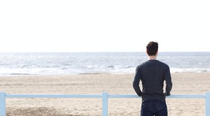 A man standing alone looking out on the Dutch coast