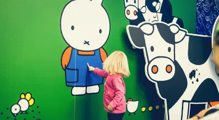 Child pointing at a mural of Nijntje
