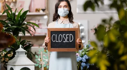 Florit with mask holidng closed sign