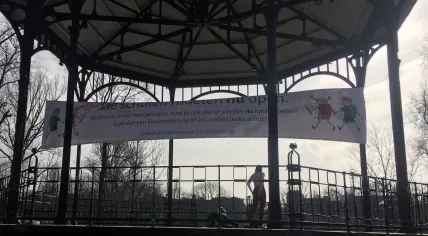 Two people working out in the Amsterdam Oosterpark under a banner calling for all schools in the Netherlands to reopen, 19 February 2021