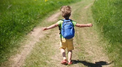 A boy running along the country road among the fields. 