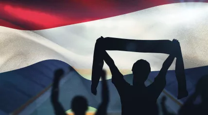Silhouettes of football fans against the Dutch flag.