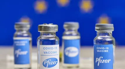 Artist's rendition of Pfizer Covid-19 vaccine vials in front of the European Union flag