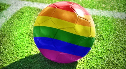 Football with rainbow flag on a field.