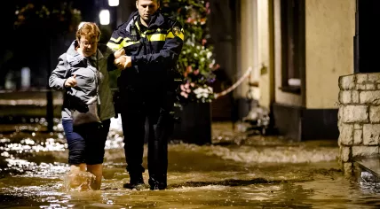 A police officer helps evacuate a Valkenburg resident forced from her home by flooding, 14 July 2021