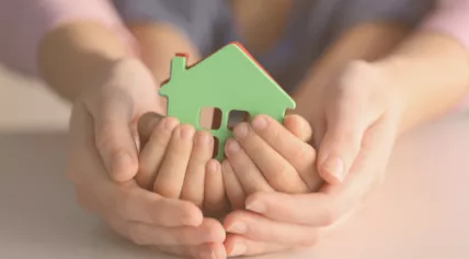 Woman holding child's hands and home