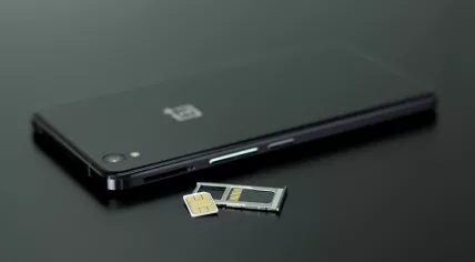 Black smart phone and SIM card on a black table