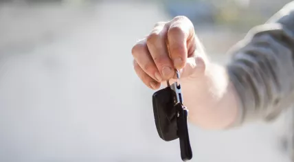 Person in grey shirt handing over car keys