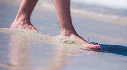 Stock image of man walking barefoot at the beach