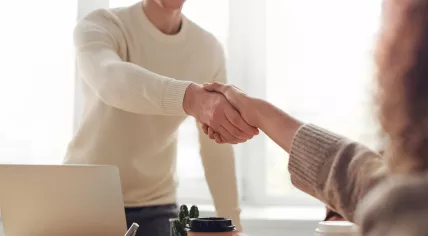 Man and woman shaking hands over a table