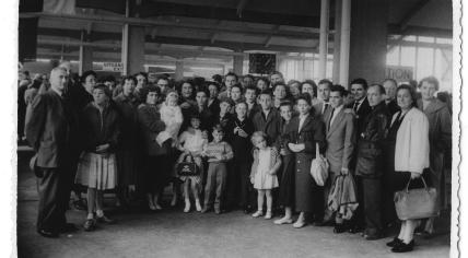 Family members wave goodbye to Mrs. G. Lampen in the departure hall of the Holland America Line as she departs for Halifax with five of her children in September 1956.