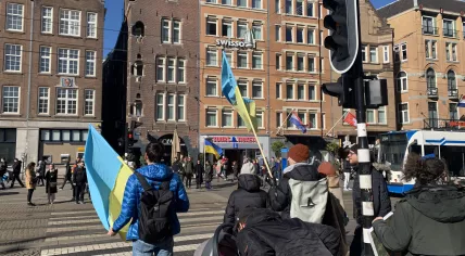 Protesters cross the street carrying Ukrainian flags at a protest against Russia's invasion of Ukraine in Amsterdam's Dam Square on Feb. 27, 2022.