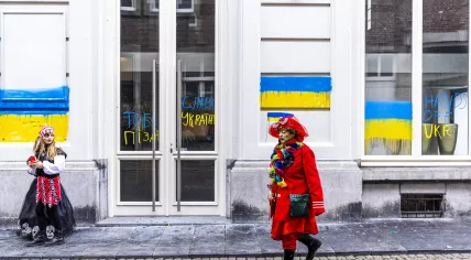 Carnival celebrators walk past pro-Ukraine graffiti on the Russian consulate in Maastricht, 1 March 2022