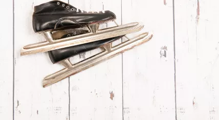 A set of tour-style ice skates against a wall