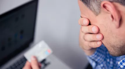 Upset man holding a credit card.