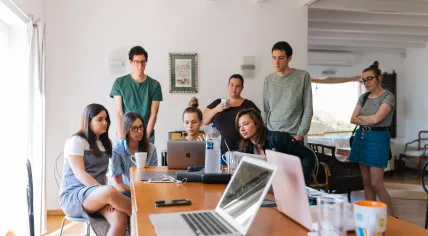 Colleagues gather round a laptop