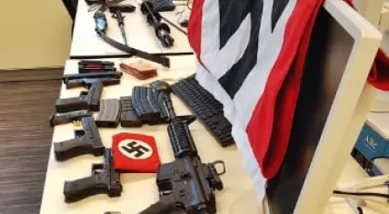 Weapons and Nazi symbols from an Utrecht man's home arranged on a table at police headquarters.