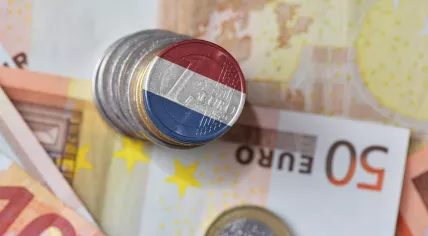 Dutch flag on a euro coin with banknotes in the background