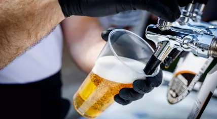 Bartender pours beer into a disposable plastic cup
