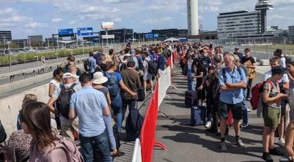 Travelers line up outside at Schiphol on Aug. 20, 2022.