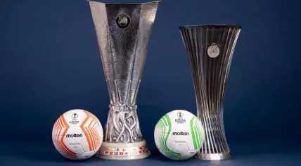 The Europa League and Europa Conference League match balls produced by Molten for the 2022-2023 season next to the tournament trophies