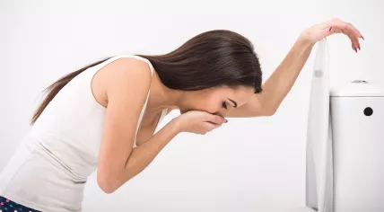 Woman vomiting over toilet.