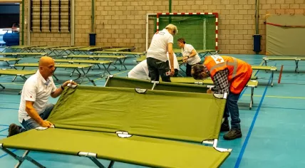 Red Cross workers setting up stretchers in a sports hall that will be an emergency shelter for asylum seekers